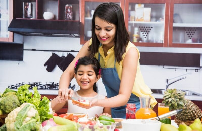 Mother and Daughter in kitchen with table full of fruits and vegetables