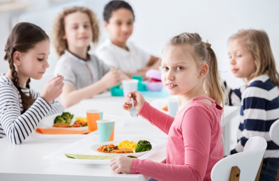 Girl eating vegetables with friends in the canteen