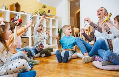 teacher with children sitting on the floor having music class, using various instruments